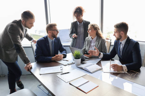 istock Group of young modern people in formalwear smiling and discussing something while working in the modern office 1198993386