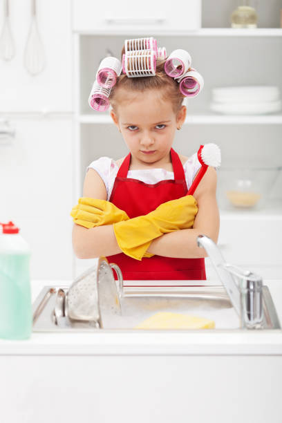istock Grumpy little girl washing dishes 1198995783