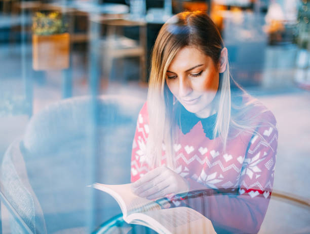 istock Woman Reading Book Behind Glass 1198995822