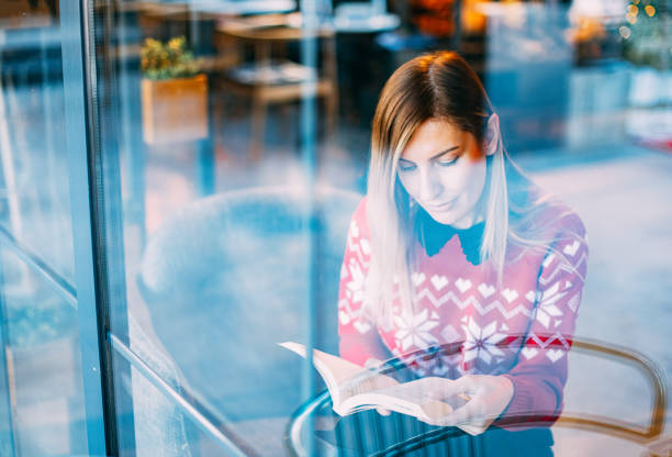istock Woman Reading Book Behind Glass 1198997271