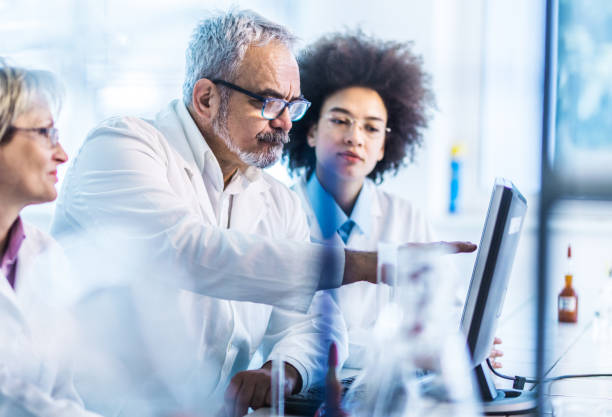 istock Team of biotechnologists working on desktop PC in laboratory. 1199000639