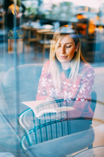 istock Woman Reading Book Behind Glass 1199000803