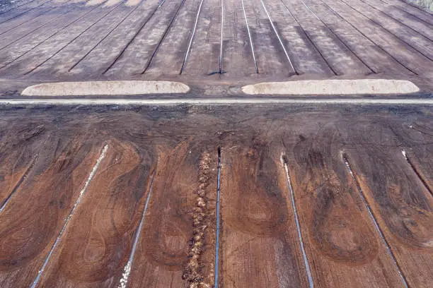 Photo of Aerial view over the peat quarry. Agricultural field, turf farm, brown soil. Bog drainage.