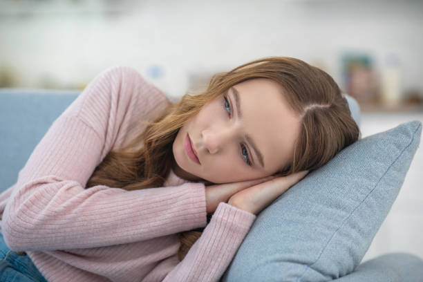 istock Sad girl lying on a sofa at home. 1199002299