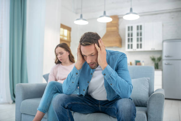 Pensive father and sad daughter sitting on couch.