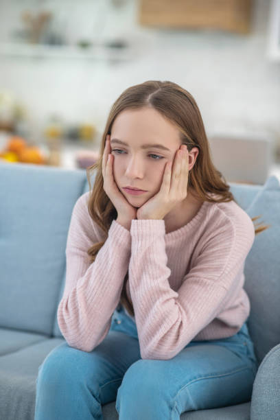 istock Pensive sad girl sitting on a sofa. 1199002336