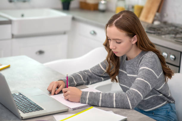 istock Pretty girl with long hair doing homework 1199002443