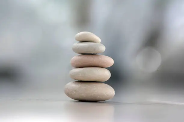 Photo of Harmony and balance, cairns, simple poise pebbles on wooden light white gray background, simplicity rock zen sculpture