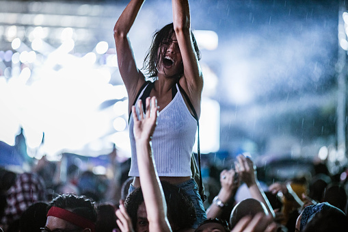 Carefree woman having fun while dancing on a rain at music concert.