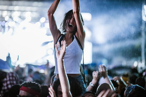 Dancing on music festival during rainy night! Carefree woman having fun while dancing on a rain at music concert. on shoulders stock pictures, royalty-free photos & images