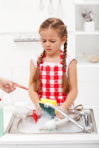 istock Do the dishes this instant - child ordered to wash up tableware 1199008783