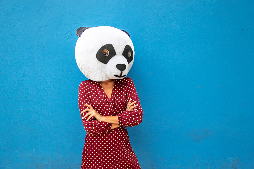 Woman with panda mask against blue wall