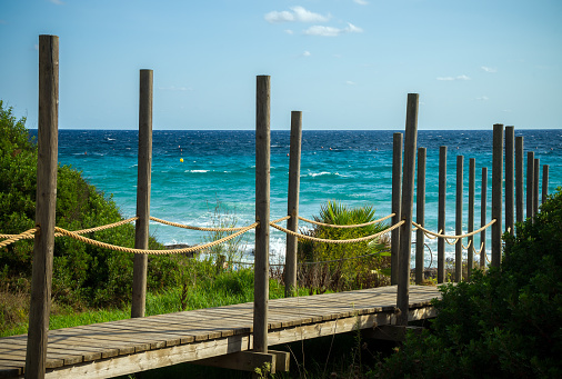 cubiertas de madera que conducen a la playa de Santo Tomás en el paisaje marino de Menorca con hermosas vistas del mar Mediterráneo, España photo