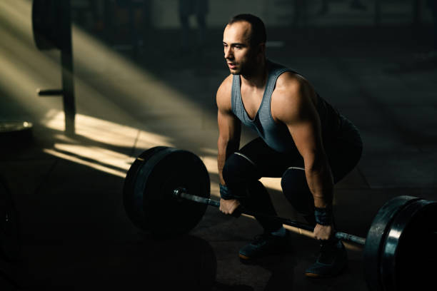istock Muscular build man performing deadlift while having weight training in a gym. 1199010083
