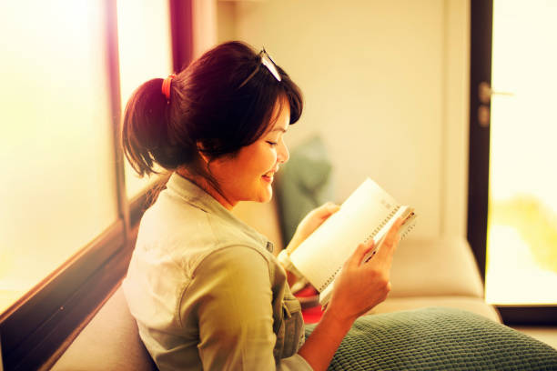 istock Young woman reading at home 1199013605