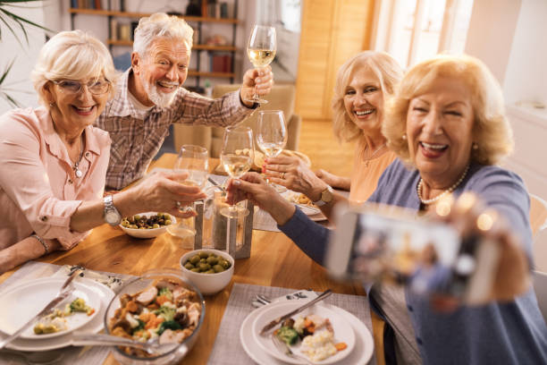 istock Group of cheerful seniors taking selfie at dining table. 1199016022