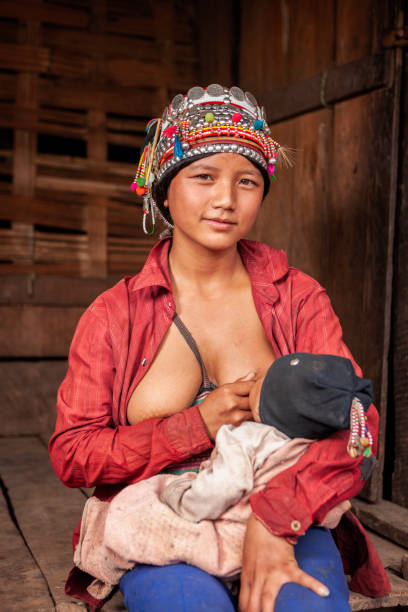 giovane donna della tribù della collina di akha che allatta il suo bambino - povertà asia foto e immagini stock
