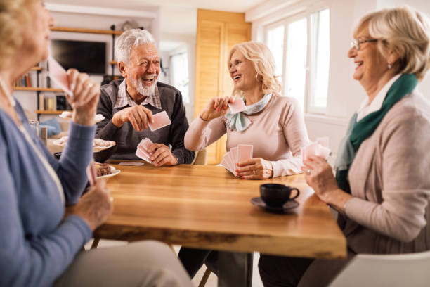 alegres amigos mayores divirtiéndose mientras juegan a las cartas juntos. - bridge juego de cartas fotografías e imágenes de stock