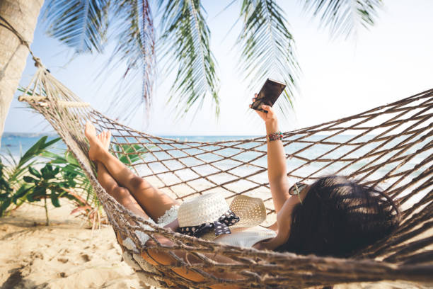 istock Happy woman with mobile phone relax in hammock 1199017974