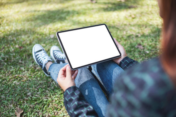 istock a woman holding and using black tablet pc with blank white desktop screen while sitting in the outdoors 1199018874