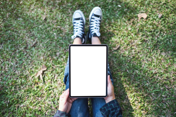 istock a woman holding and using black tablet pc with blank white desktop screen while sitting in the outdoors 1199018968