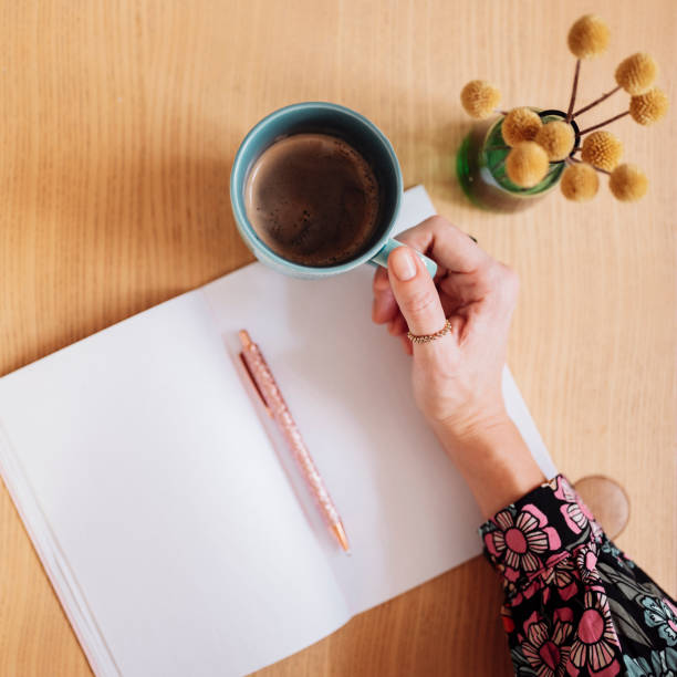istock Woman writing on blank page in notebook and having coffee 1199020646