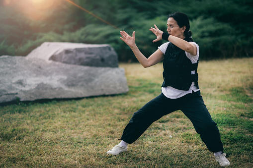 Chi Gong energy practice. Mature woman exercising in a park.