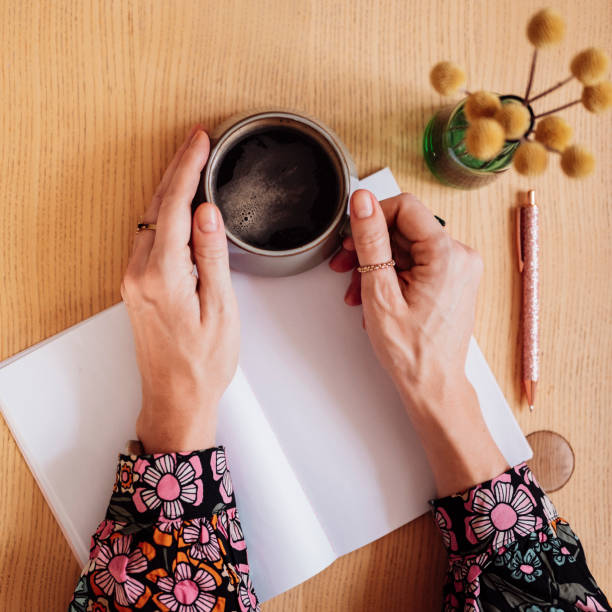 istock Woman writing on blank page in notebook and having coffee 1199023129