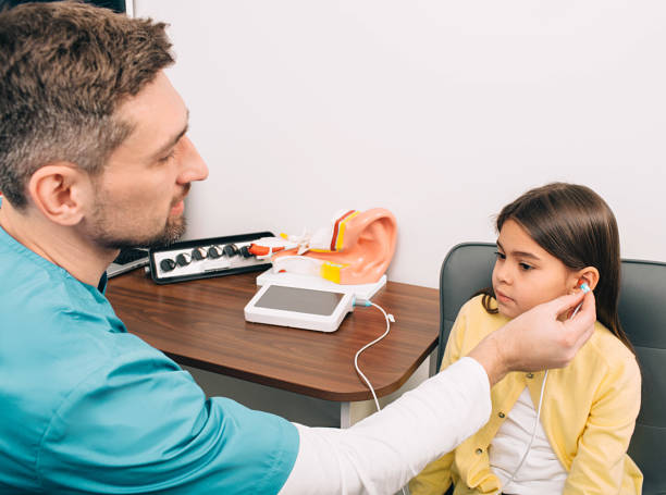 fonoaudiólogo verifica os ouvidos de uma criança. menina mestiço que tem o teste de audição, audiometria da impedância do procedimento - hearing aid audiologist audiology small - fotografias e filmes do acervo