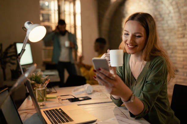 istock Happy businesswoman text messaging on mobile phone while working late. 1199025729