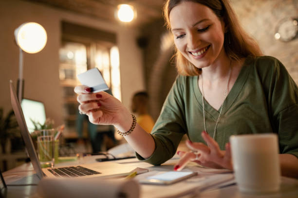 feliz empresaria e-banking con tarjeta de crédito y teléfono móvil en la oficina. - spending money fotos fotografías e imágenes de stock