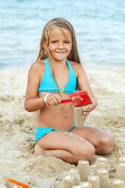 Photo of Little girl playing with sand on the beach