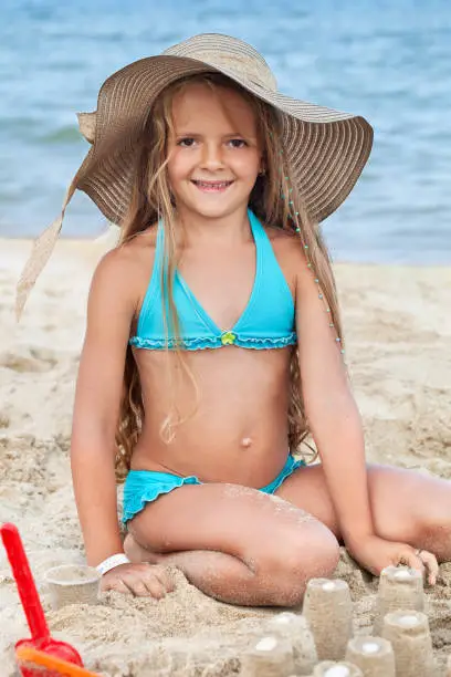 Photo of Happy child building sand castles on the beach