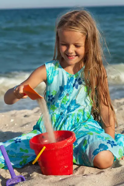 Photo of Little girl playing with sand on the beach