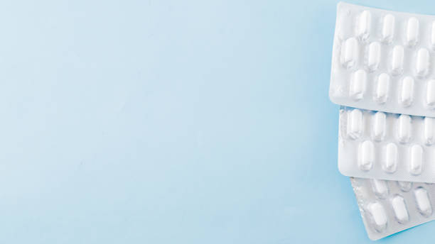 istock White blister capsules on a blue background. Pharmacy background 1199027459