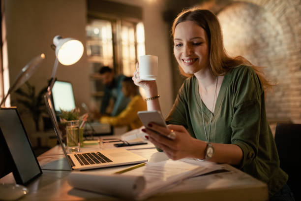 istock Smiling freelancer texting on cell phone and drinking coffee in the office. 1199027737