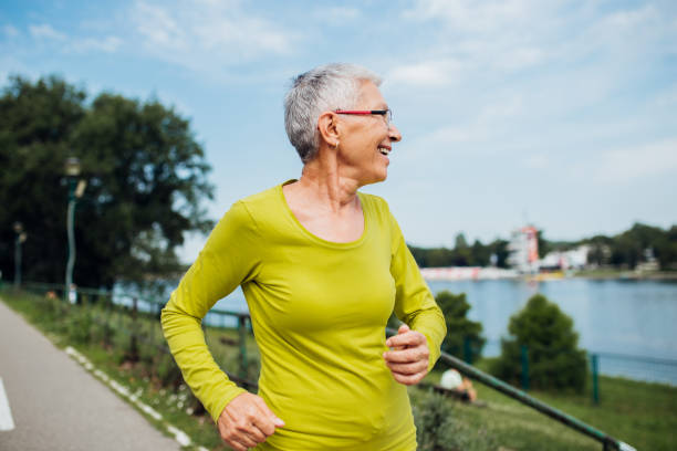 istock Grayhair lady running next to the river 1199028625