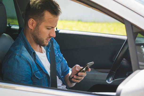 istock Young man inside a car holding a mobile phone. 1199031996