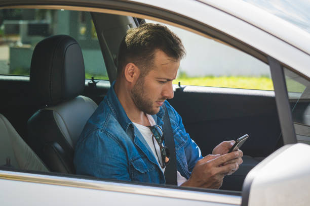 istock Young man inside a car holding a mobile phone. 1199032273