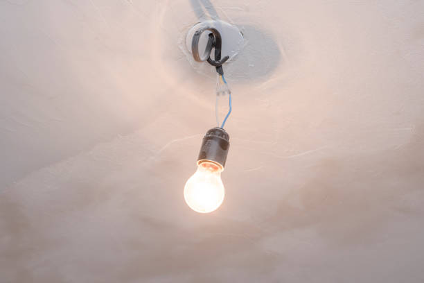 istock Light bulb hanging on wires on white ceiling 1199034379