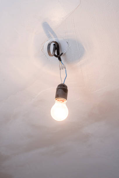 istock Light bulb hanging on wires on white ceiling 1199034396