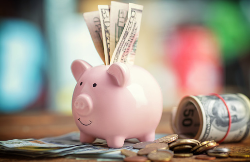 pink piggy bank with money on table