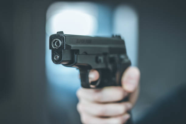 istock Crime or robbery concept: Man with black gun is aiming with his weapon 1199034888