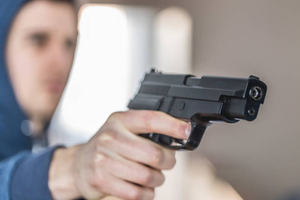 istock Crime or robbery concept: Man with black gun is aiming with his weapon 1199035212