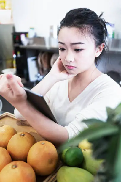 A female clerk in a juice shop focuses on viewing information using mobile electronic devices