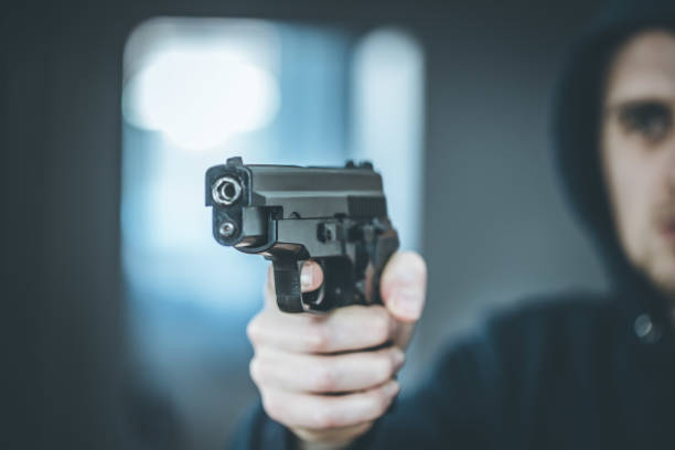 istock Crime or robbery concept: Man with black gun is aiming with his weapon 1199035809