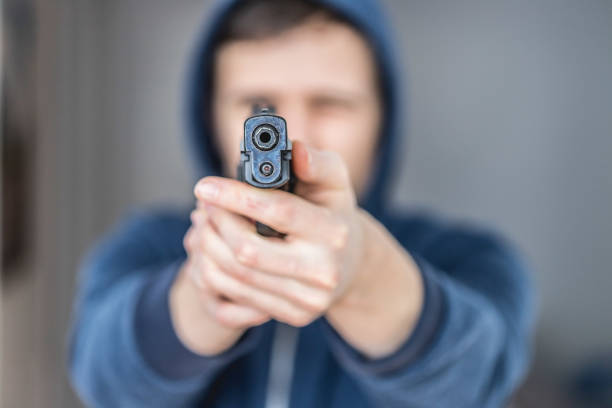 istock Crime or robbery concept: Man with black gun is aiming with his weapon 1199035898