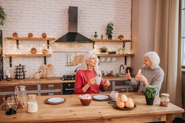 istock Two mature grey-haired positive ladies looking photos in internet 1199038192