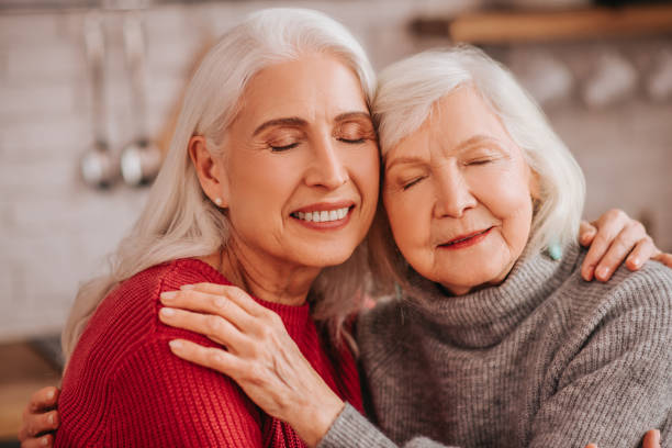 istock Two mature grey-haired positive ladies hugging each other 1199038201