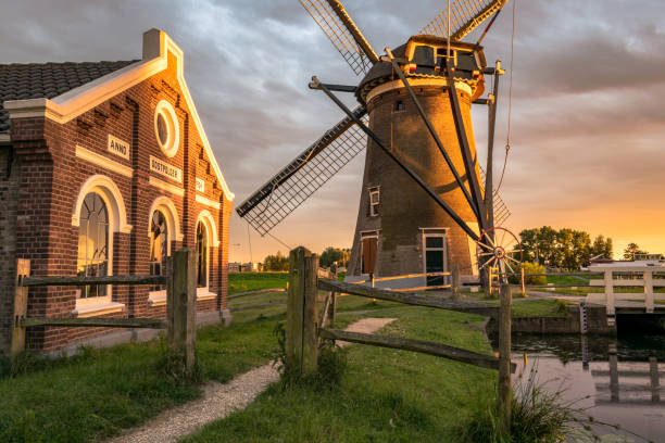 Windmill `Mallemolen` and pumping station in Gouda, Holland at sunset. Scenic typical dutch photograph of a windmill in the golden evening light. gouda south holland stock pictures, royalty-free photos & images